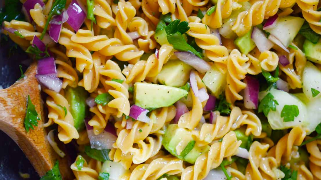 A closeup of avocado pasta salad in a bowl.