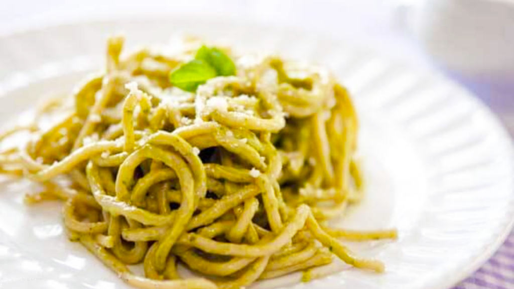 A closeup of a pile of spaghetti covered in avocado pesto alfredo sauce.