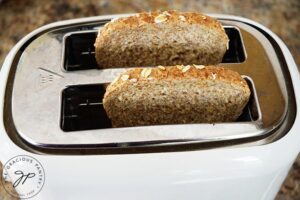 Two slices of toast sitting in a white toaster.