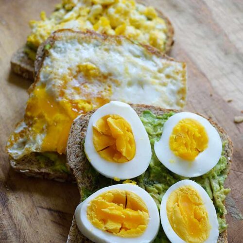 A row of three slices of Avocado Toast With differently made egg on each of them.