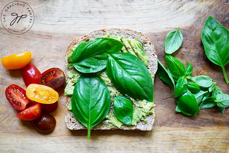 Basil leaves laid across the avocado bread.