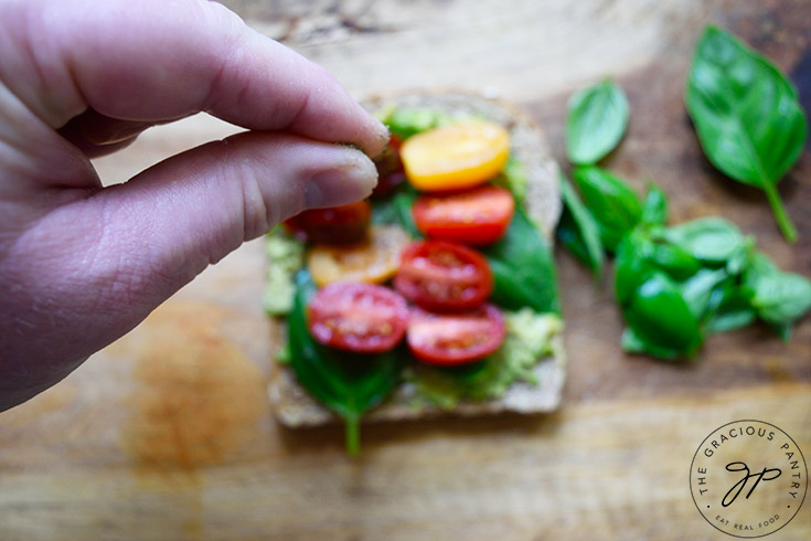 Sprinkling ground pepper on the toast.