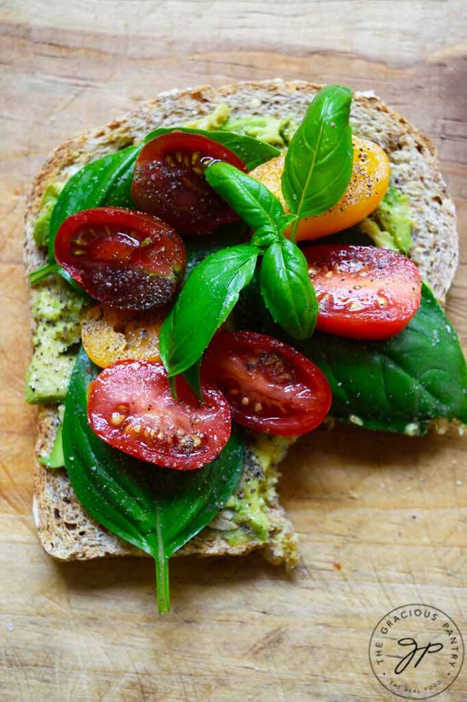 A slice of Avocado Toast With Tomato with a bite taken from it.