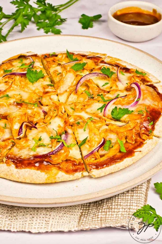 A side view of a cut BBQ Chicken Pizza on a plate.