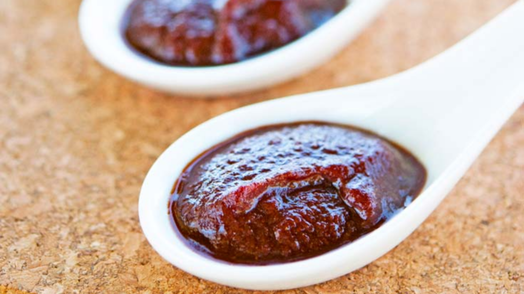 Two white spoons filled with bbq sauce.