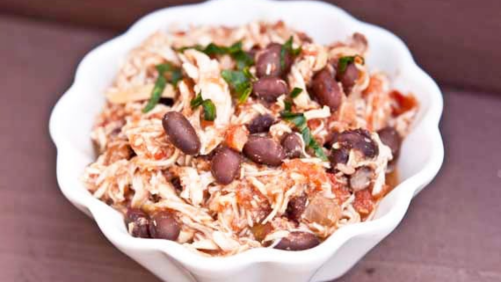A white fluted bowl holds Mexican Chicken and Beans.