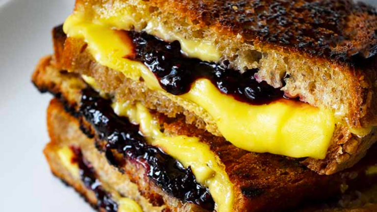 A closeup of a stacked grilled cheese with blackberries.