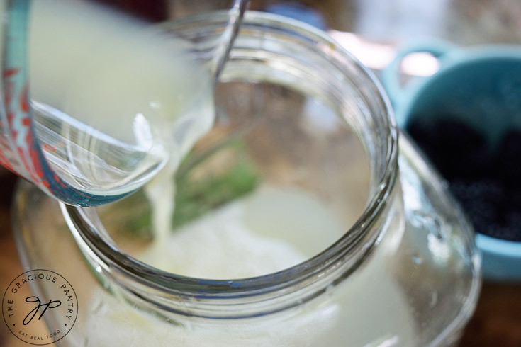 Pouring lemon juice into a large beverage jug.