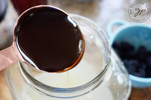 Pouring honey into a large beverage just with water and lemon juice.