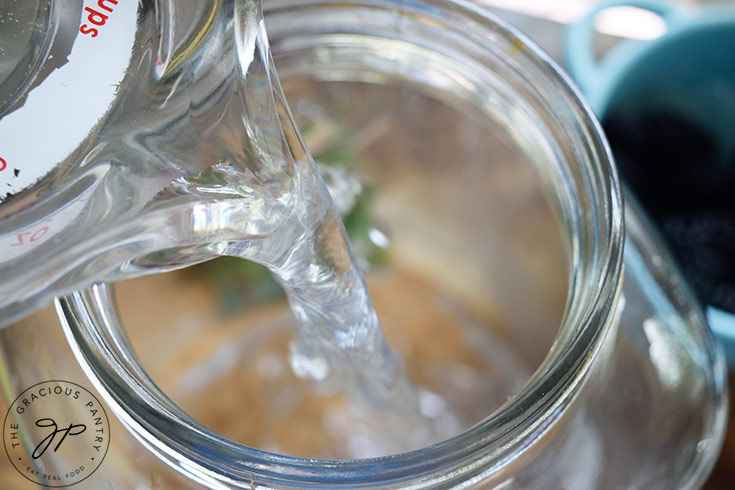 Pouring water into a large beverage jug.