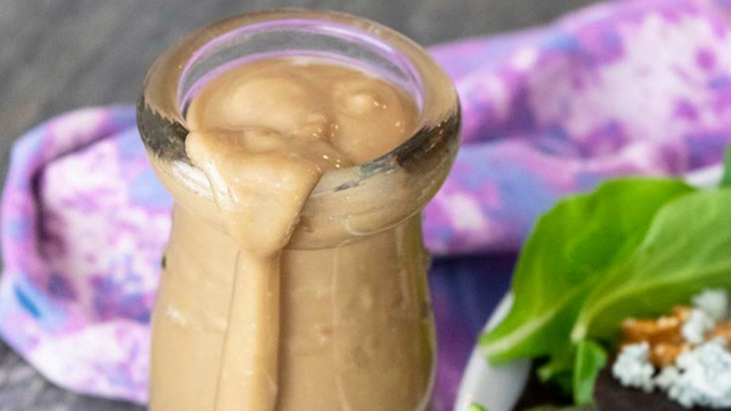 A bottle filled with blue cheese vinaigrette dressing with a bit of the dressing running down the front of the bottle.