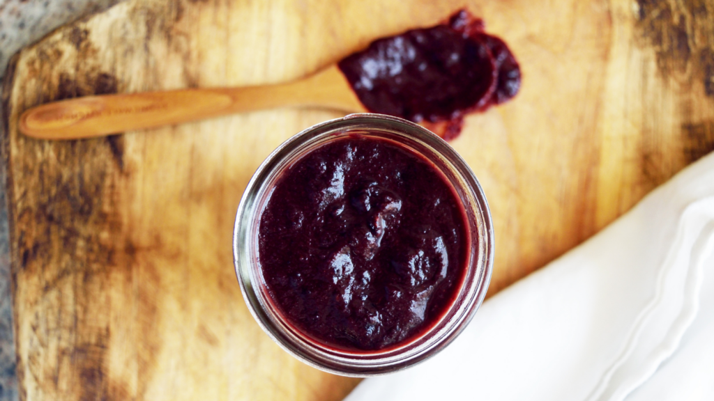 An overhead view of a glass jar filled with blueberry bbq sauce.
