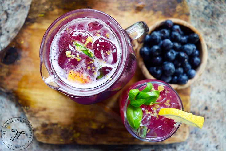 An overhead view of a glass pitcher and a glass next to each other, both filled with Blueberry Lemonade.