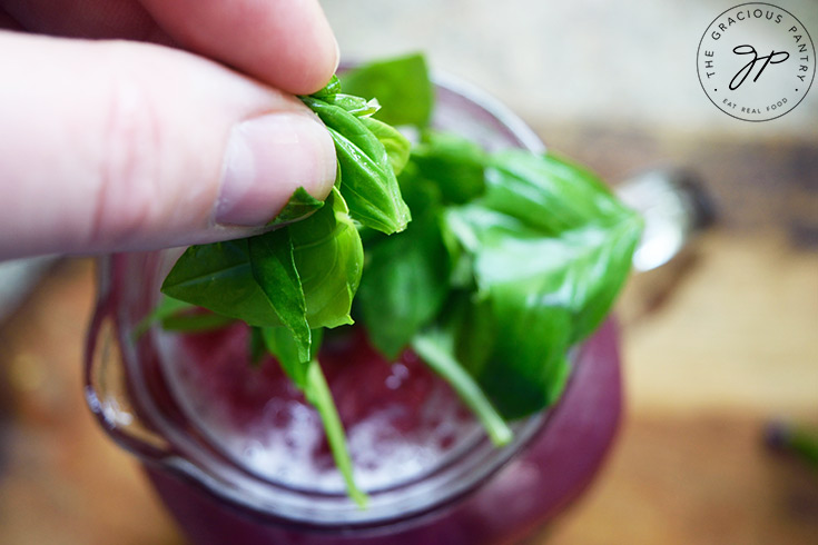 Adding fresh basil leaves to a pitcher of Blueberry Lemonade.