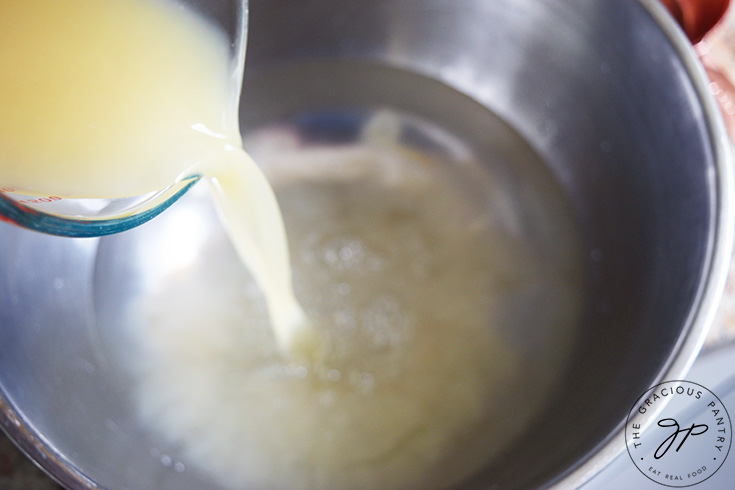 Pouring lemon juice into a large mixing bowl with water.