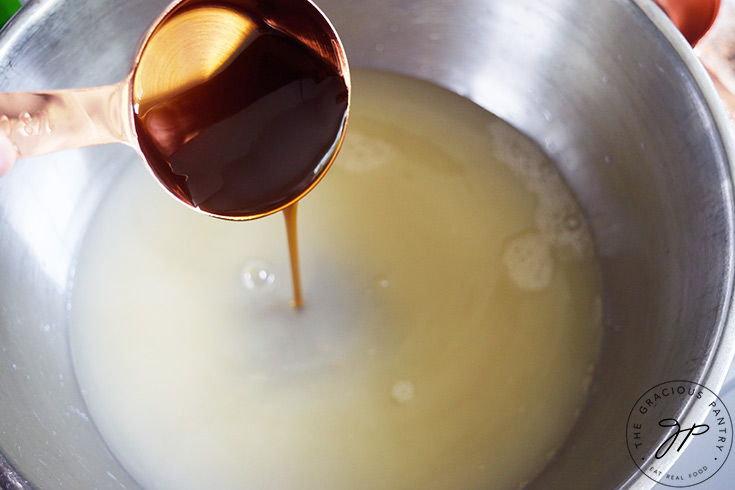 Pouring sweetener into a mixing bowl of water and lemon juice.