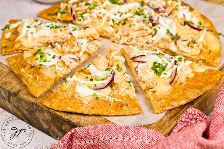 A baked and sliced Buffalo Chicken Pizza on a wood cutting board.