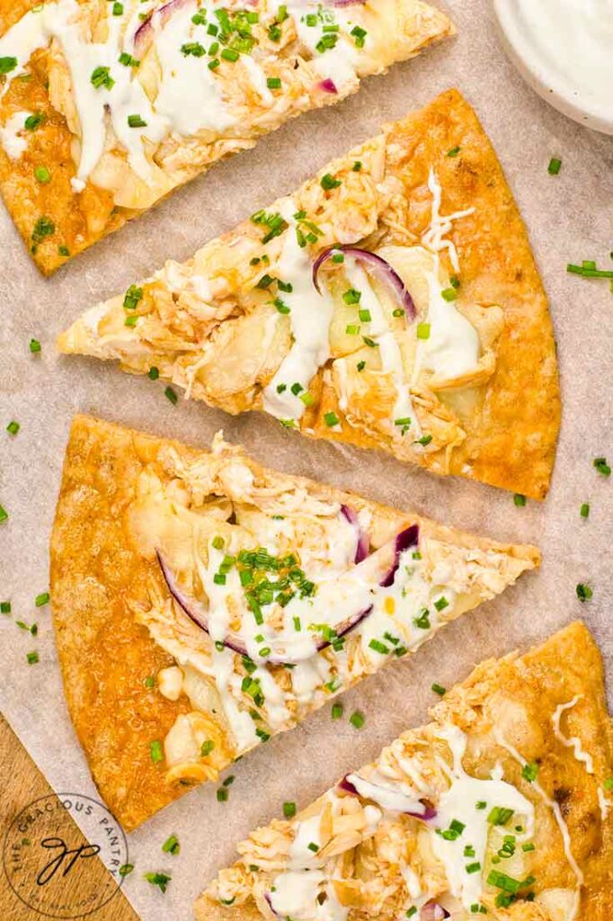 Slices of Buffalo Chicken Pizza arranged in a row on parchment paper.