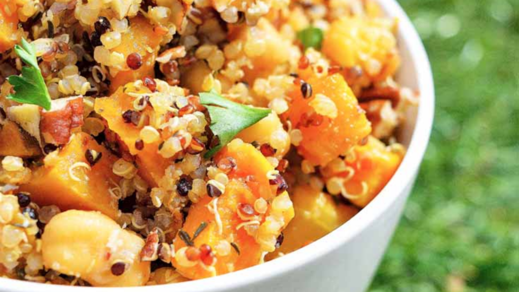 A closeup of a white bowl filled with butternut pecan quinoa salad.