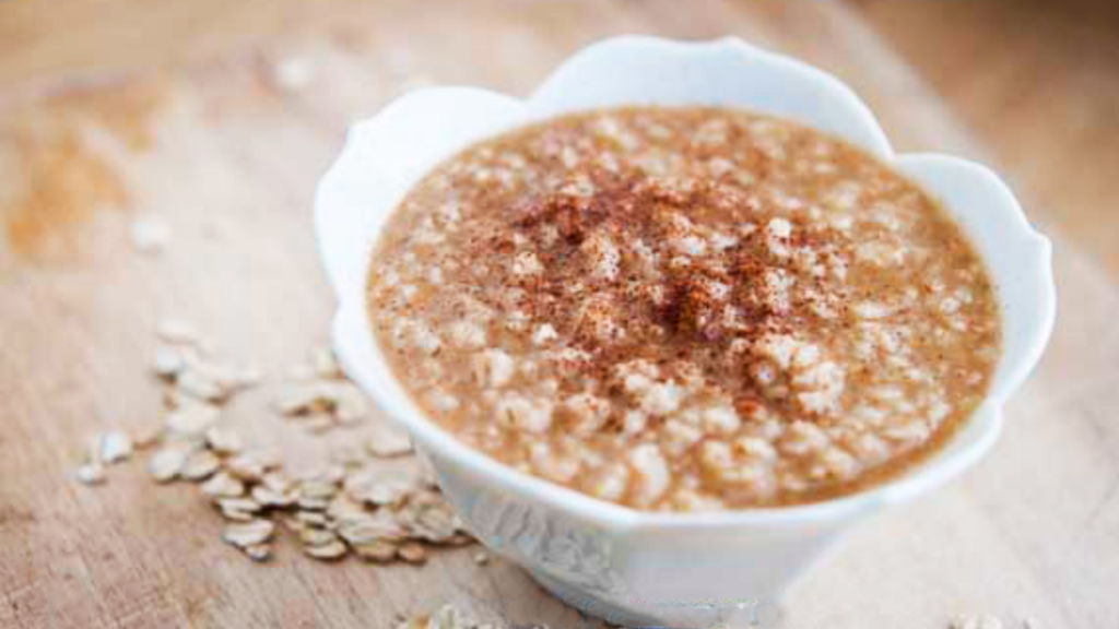 A white, fluted bowl full of buttery cinnamon oaatmeal.