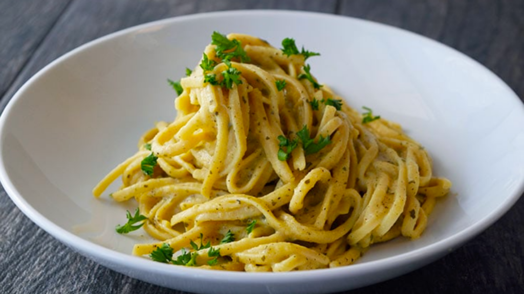 A white bowl holds a nest of diary free carbonara.