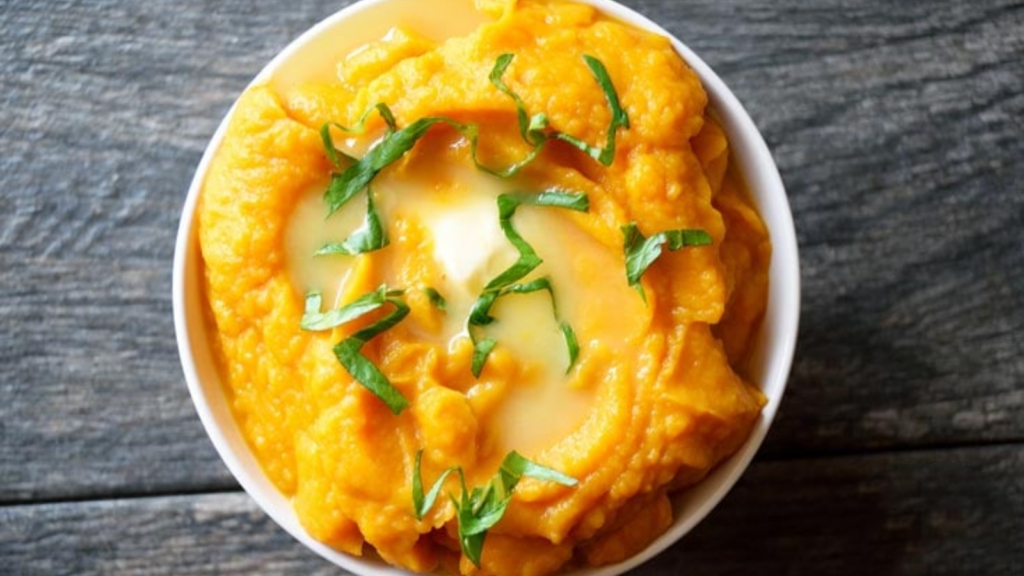 An overhead view of a white bowl filled with cauliflower sweet potato mash.