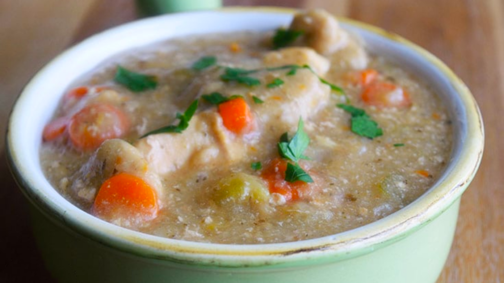 A closeup of a light green crock filled with chicken and dumplings.