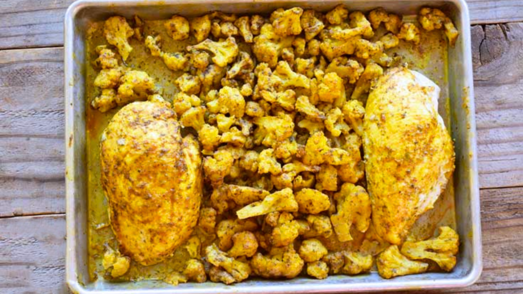 An overhead view of a sheet pan holding a chicken and cauliflower dinner.