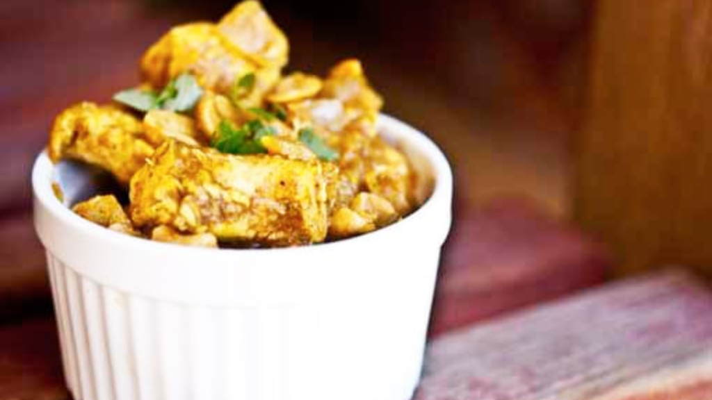 A small white bowl holds a serving of chicken korma.