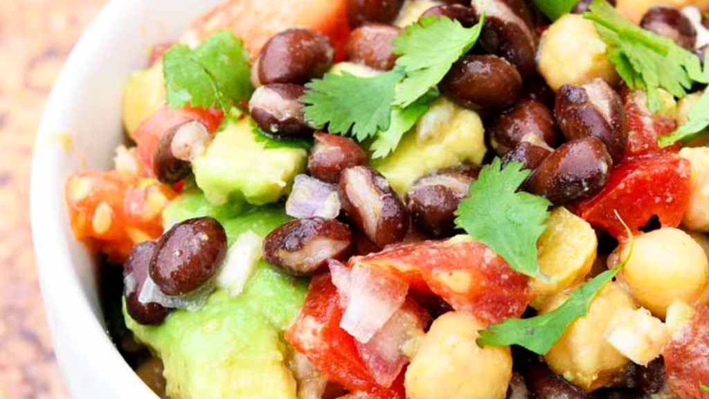 An up close view of a white bowl filled with chickpea black bean salad.