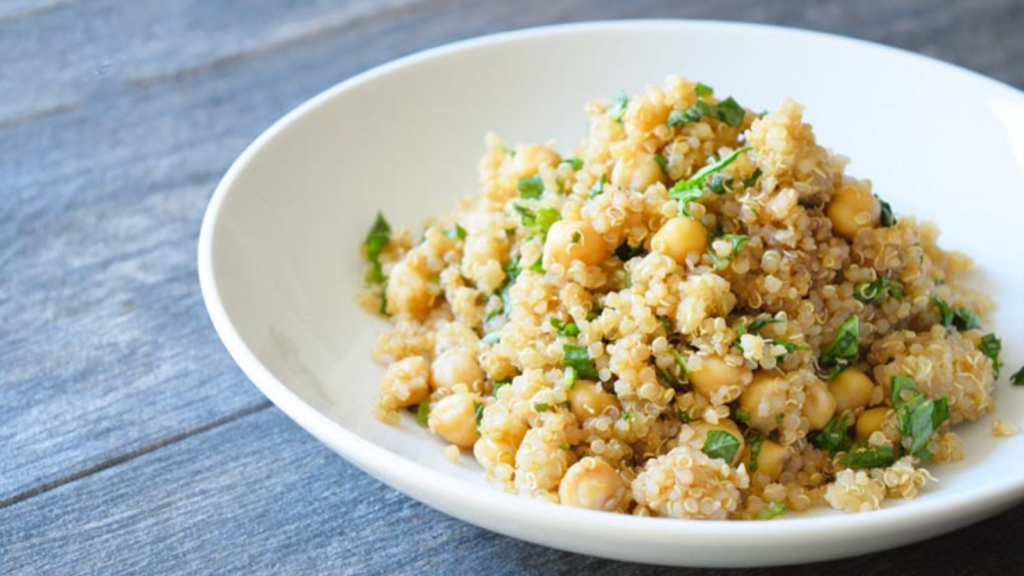 A side view of a white bowl filled with chickpea quinoa salad.