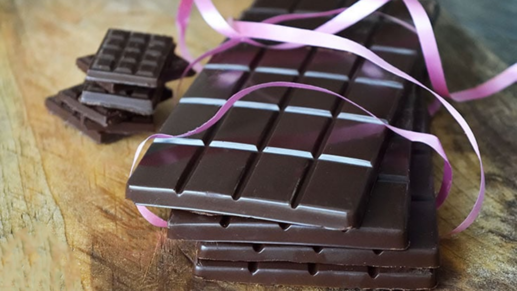 A stack of chocolate bars with gift ribbon loosely wrapped around them.