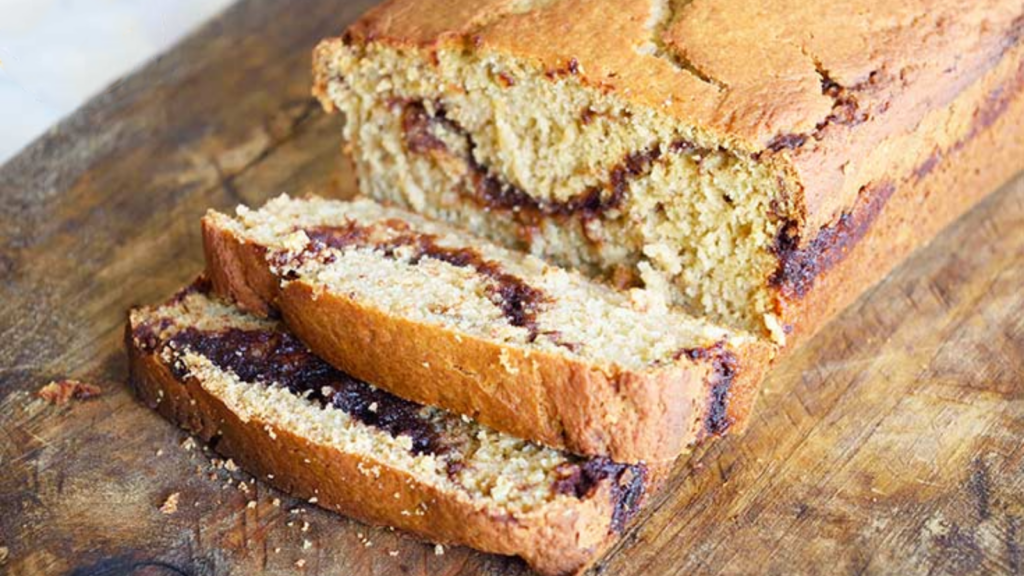 Two slices of cinnamon bread have been sliced off the front of a loaf on a cutting board.