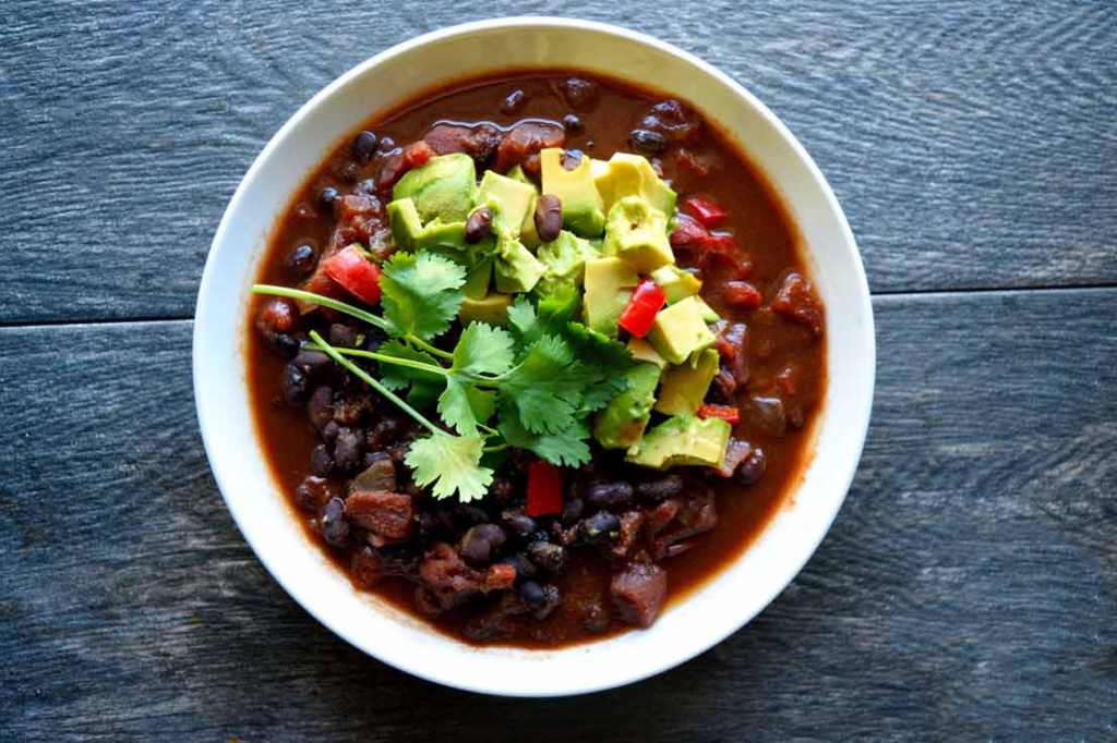 An overhead view of a white bowl filled with Mexican black bean chili.