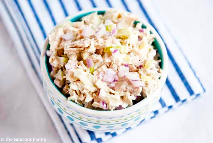 An overhead view of a decorative bowl holding a serving of traditional tuna salad.