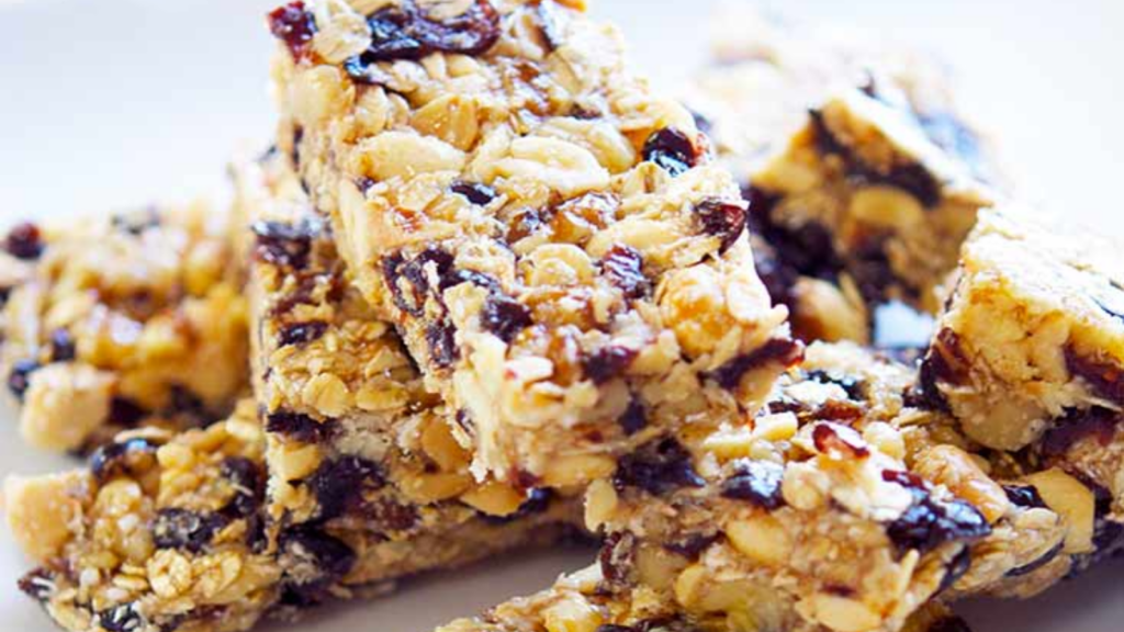 A pile of coconut granola bars on a wood surface.