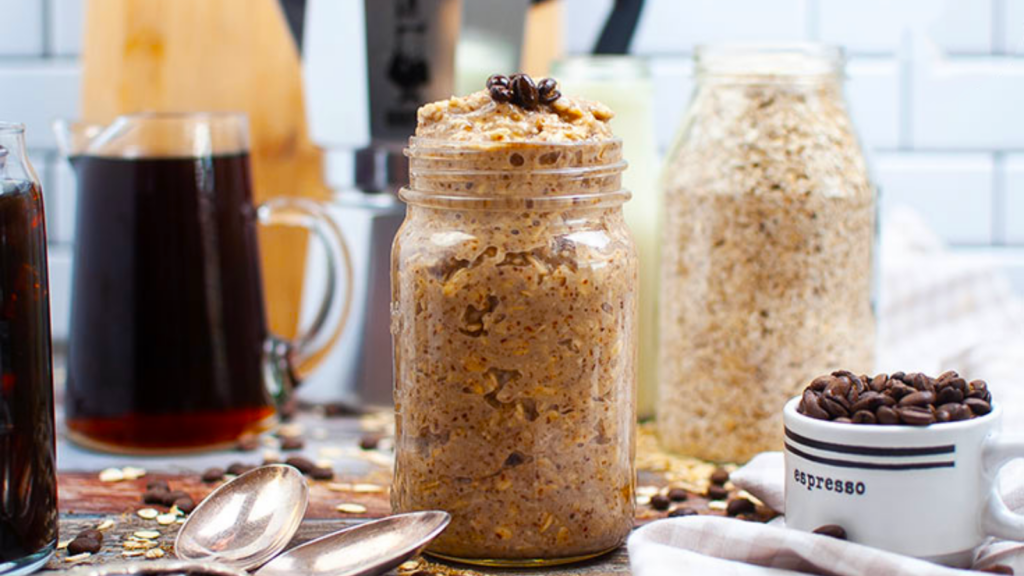 A mason jar full of coffee overnight oats and garnished with roasted coffee beans.