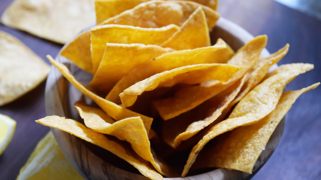 A wooden bowl filled with homemade corn chips.