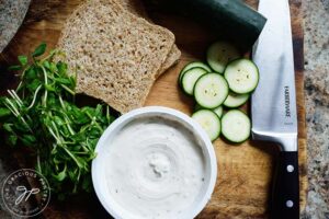 Ingredients for a cucumber sandwich sitting on a wood cutting board.