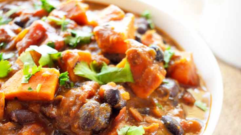 A closeup of a white bowl filled with curried sweet potato chowder.