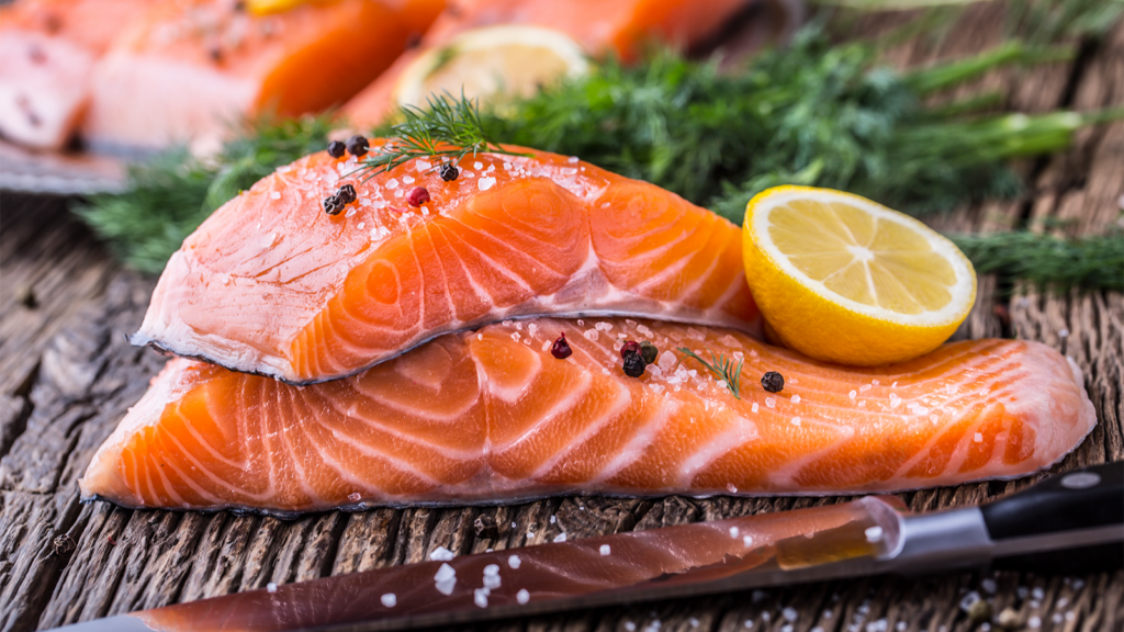 Raw salmon fillets on a wood cutting board.