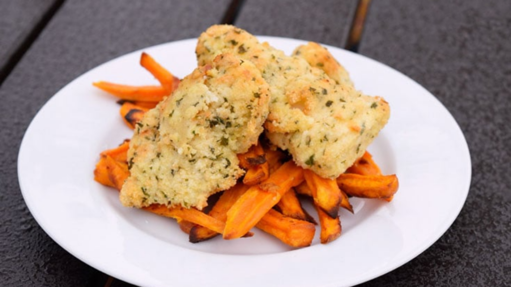 A white plate holds some air fryer fish n' chips. The chips are sweet potato fries.