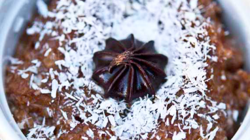 A closeup of a white bowl holding german chocolate oatmeal. A chocolate kiss sits in the middle.