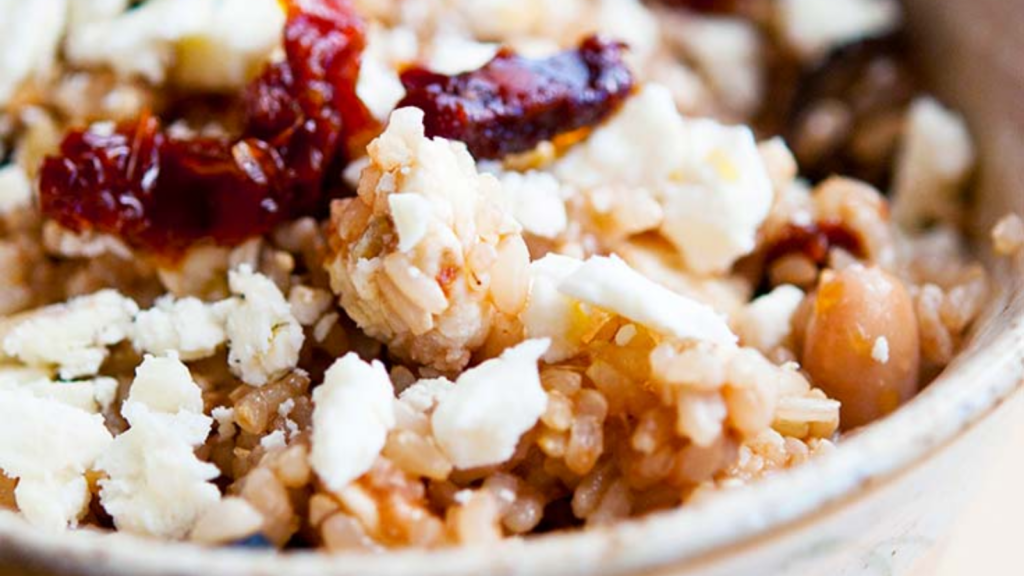 A closeup of a Greek rice bowl with sun dried tomato pieces.
