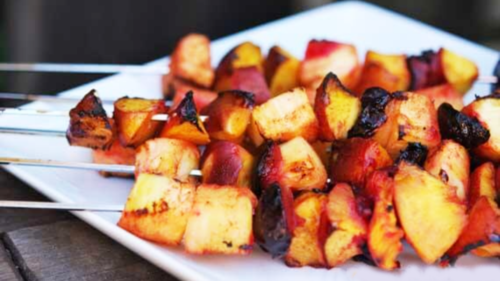 Fruit kabobs stacked up on a white platter.