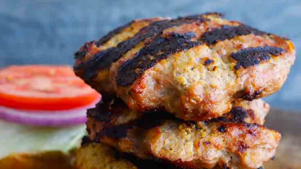 A closeup of grilled turkey patties stacked up on each other.