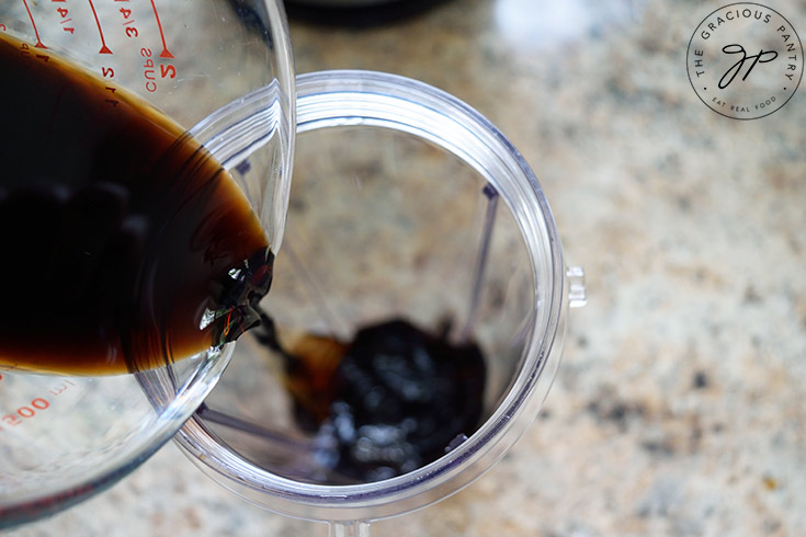 Pouring balsamic vinegar into a blender tumbler.