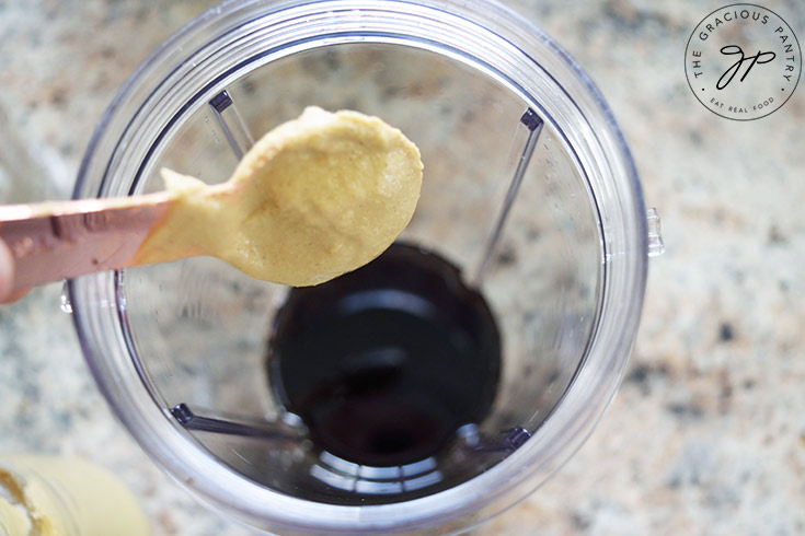 Adding mustard to a blender tumbler.