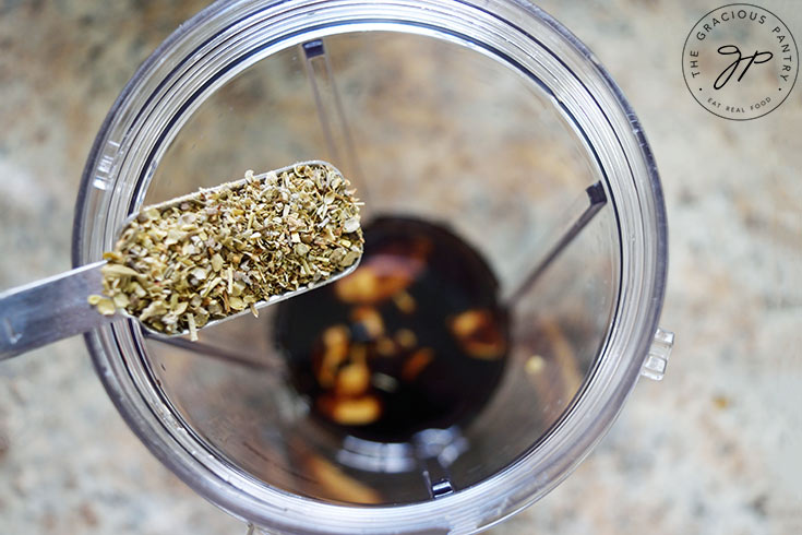 Adding Italian herbs to a blender tumbler.