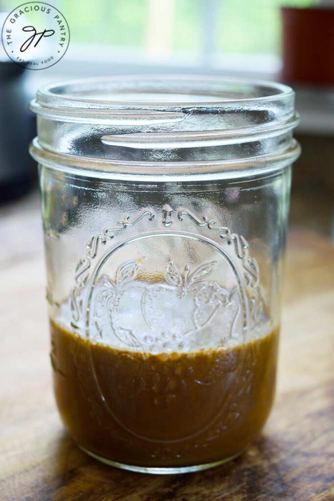 A side view of a partially full mason jar which holds Healthy Balsamic Vinaigrette.